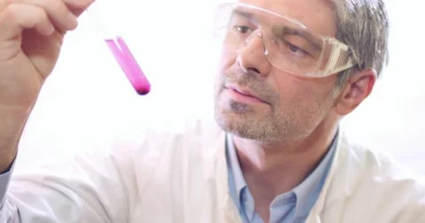 A young scientist holding, mixing and looking at a test tube Stock Footage 48977945