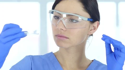 Young Scientist Looking at Blue Solution in Test Tube in Laboratory Stock Footage 81054874