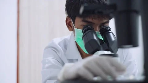 Young  scientist looking at microscope with sample on plate in Medical lab Stock Footage 133444742