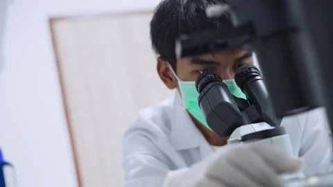 Young  scientist looking at microscope with sample on plate in Medical lab Stock Footage 134273761