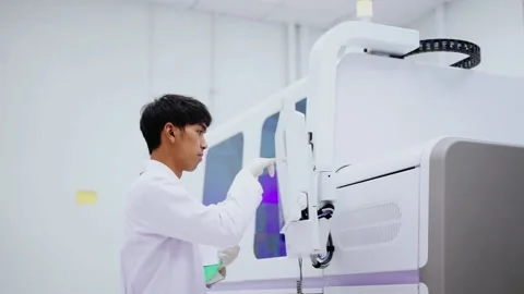 Young scientist looking at results from automation blood analyzer report in medi Stock Footage 133444834