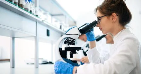 Young scientist looking through microscope in laboratory Stock Photos