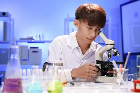 Young scientist looking through a microscope in the laboratory. Stock Photos