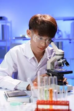 Young scientist looking through a microscope in the laboratory. Stock Photos