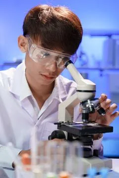 Young scientist looking through a microscope in the laboratory. Stock Photos