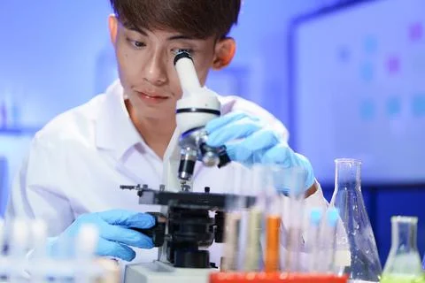 Young scientist looking through a microscope in the laboratory. Stock Photos