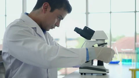 Young scientist man looking through microscope in laboratory Stock Footage 201362271