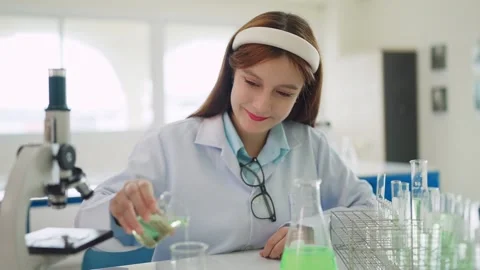 Young scientist mixes green liquid in lab Stock Footage 340448700