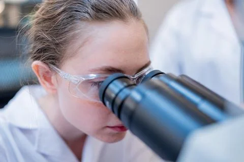 Young scientist observes samples through a microscope in a laboratory setti.. Stock Photos