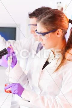 Young scientist pipetting red solution. Stock Photos