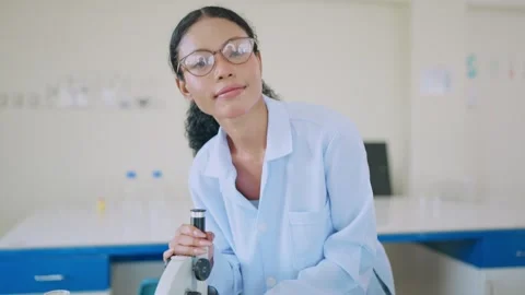 Young scientist smiles while examining samples through microscope Video stock 338011204