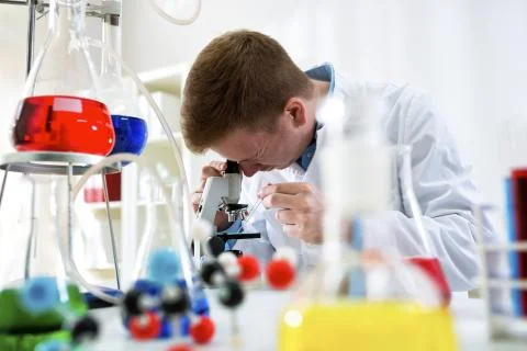 Young scientist working with microscope at the clinic laboratory Stock Photos