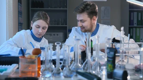 Young scientists are talking at table during working day in pharmaceutical Stock-Footage 128297779