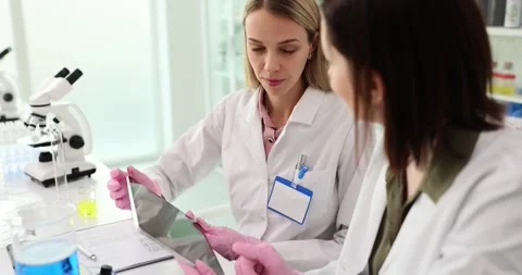 Young scientists with tablet computer and microscope perform tests or research Vidéo 263888188