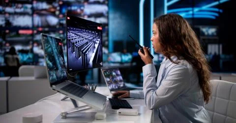 Young Security Guard Monitors Multiple CCTV Cameras While Using Laptop In Con Stock Photos