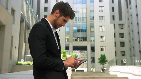 Young serious businessman using tablet and enjoying great summer day out of Stock Footage 73813179