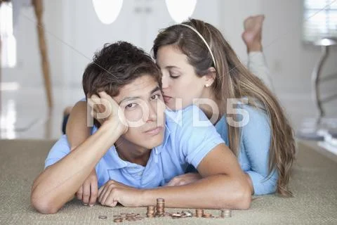 A young serious couple lying on the floor near stacks of coins Stock Photos