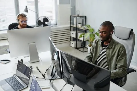 Young serious diversity programmer in casual clothes looking at computer screen 写真素材