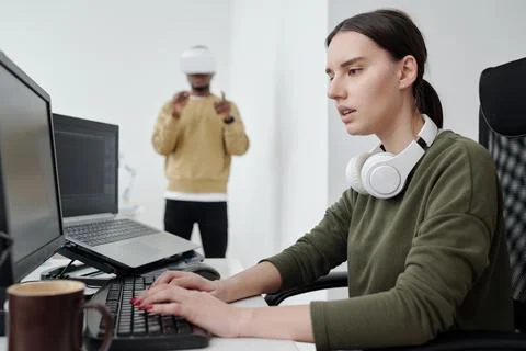 Young serious female programmer decoding data and looking at computer screen Stock Photos