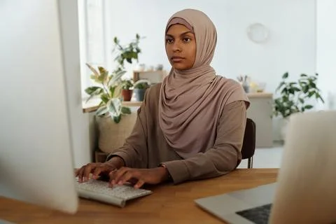 Young serious female programmer looking at computer screen during work 스톡 사진