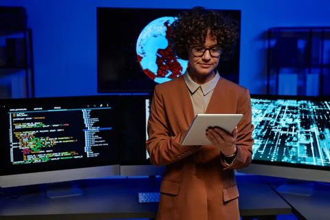 Young serious female programmer using tablet against computers Stock-Fotos