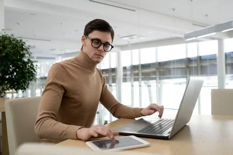 Young serious high-tech developer using tablet and laptop Stock Photos