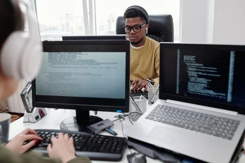 Young serious male programmer looking at computer screen during network 스톡 사진
