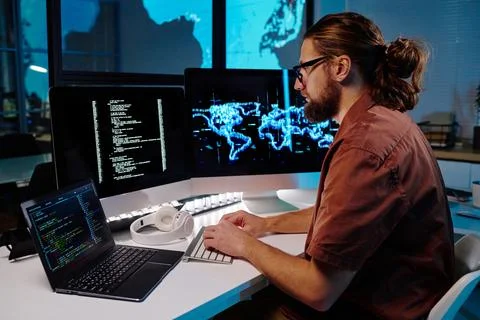 Young serious male programmer looking at coded data on computer screen Foto stock