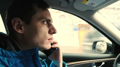 Young serious man drinking coffee and speaking on the phone sitting in car Vídeo Stock 132277123