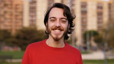 Young serious man staring at camera changes expression smiling - outdoor Video stock 142878534