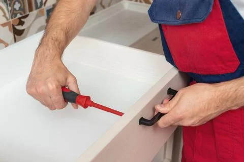 Young service contractor assembling new furniture in kitchen Stock Photos