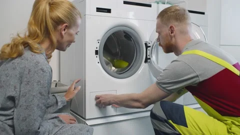 Young service man installing new washing machine and shaking hands with woman Stock-Footage 138215937
