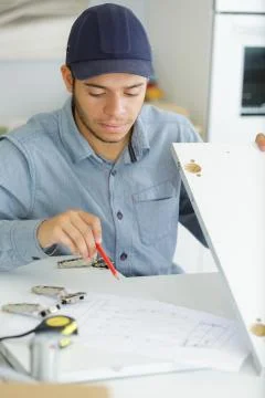 Young serviceman assembling kitchen cupboard Stock Photos