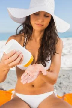 Young sexy brunette with straw hat putting on sun cream Stock Photos