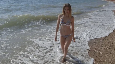 Young sexy model in bikini walking cross sea wave beach wide angle, slow motion Stock Footage 100430632