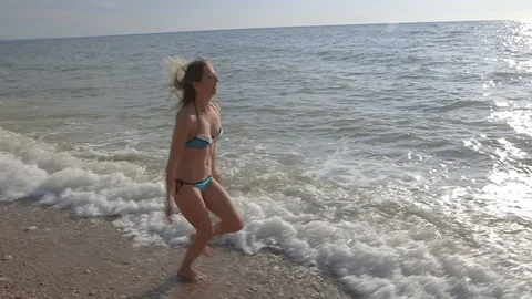 Young sexy model in bikini walking cross sea wave beach wide angle, slow motion Stock Footage 100433906