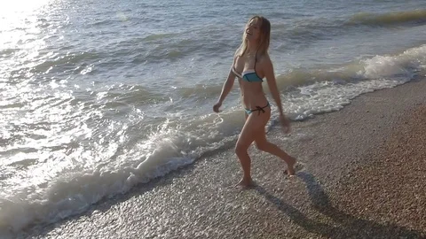 Young sexy model in bikini walking cross sea wave beach wide angle, slow motion Stock Footage 100435051