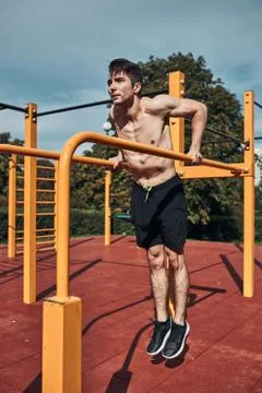 Young shirtless bodybuilder doing dips on parallel bars during his workout in Foto stock