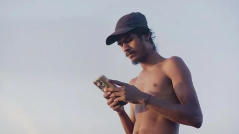 Young shirtless Indian male using smartphone next to salt pan flats, Mumbai  Stock Footage 337092964