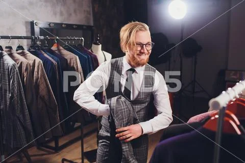Young shopaholic man chousing jacket at boutique. Stock Photos