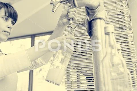 Young shopkeeper pouring delicious organic juice into glass bottle at zero waste Stock Photos