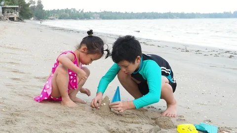 Young siblings playing sand on the beach Stock Footage 89992152