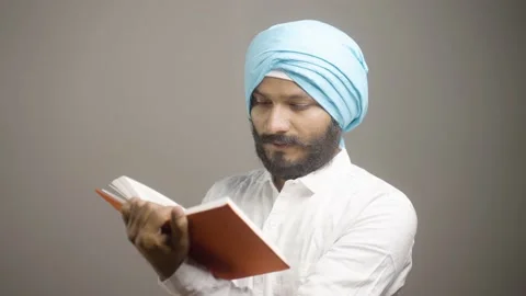 Young sikh man reading holy religious Scripture for praying god on grey Stock Footage 168822899