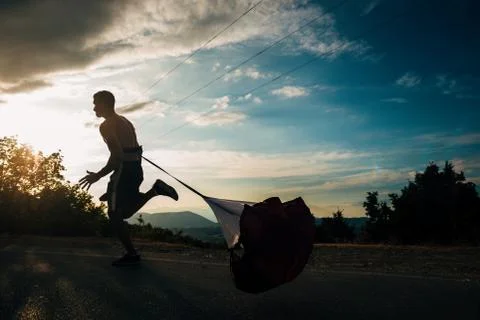 Young silhouette sprinter exercise jogging while wearing parachute Fotos de archivo