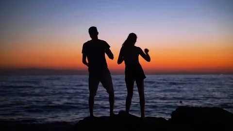 Young Sillhouetted Couple Having Fun and Dancing at Sunset on Beach by Ocean. Stock Footage 129186294