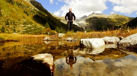 Young single caucasian man standing alone in mountain scenery. water reflection 動画素材 42947482