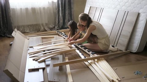 Young single mother with kids assembling wooden slats of an orthopedic base of a Stock Footage 204721642