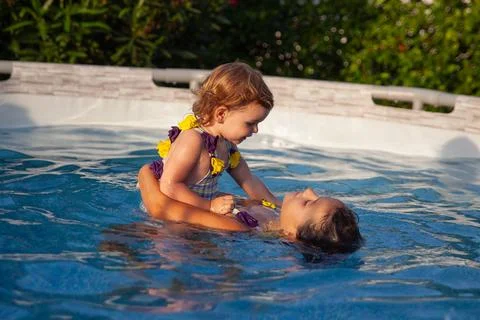 Young sisters expressing love while playing in pool Foto stock