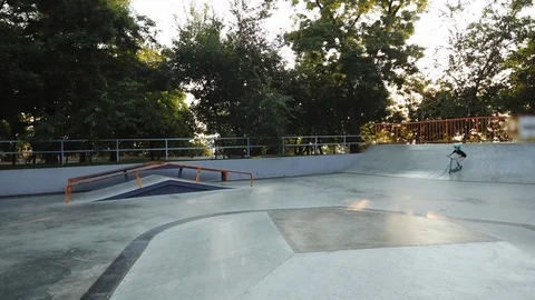 Young skater performs tricks riding scooter on skate park Stock Footage 120145913
