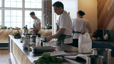 Young skillful chefs cooking and preparing food in pots and pans in interior kit Stock Footage 199457546